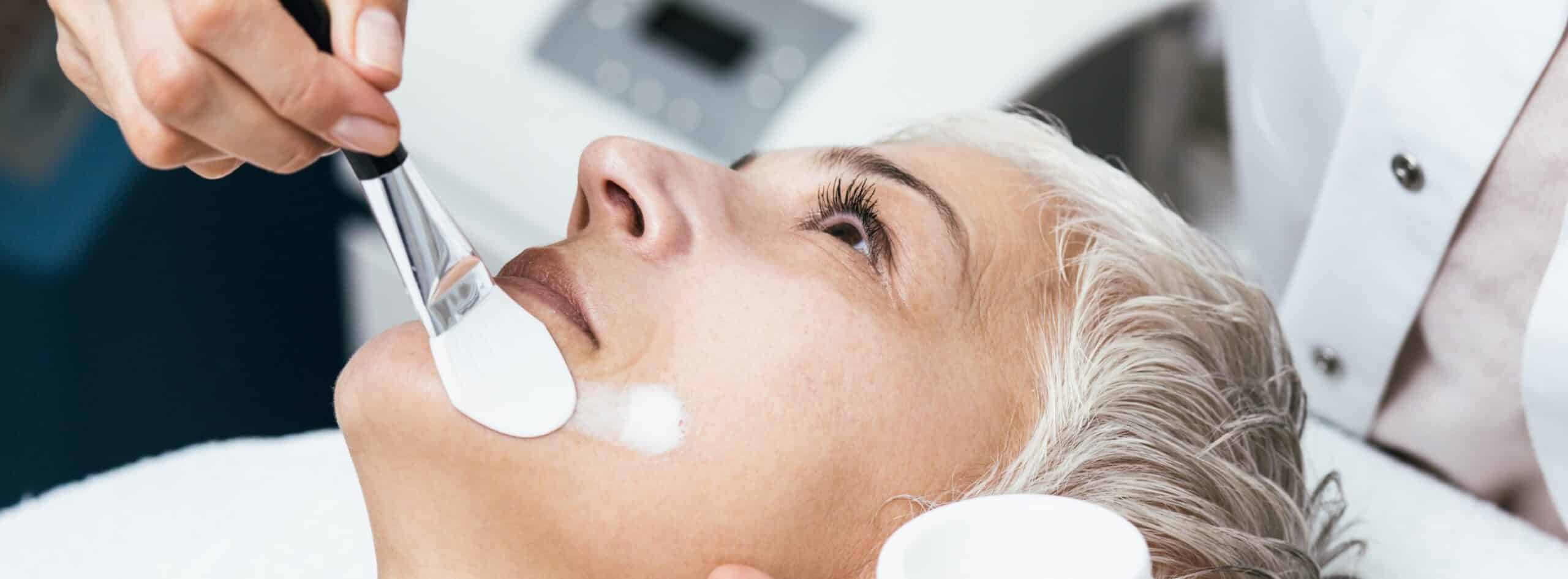 Photo du visage d une femme allongee recevant un soin esthetique - peeling chimique | Dr Santini Paris 16