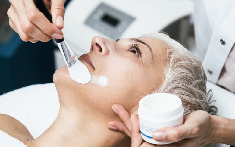 Photo du visage d une femme allongee recevant un soin esthetique - peeling chimique | Dr Santini Paris 16